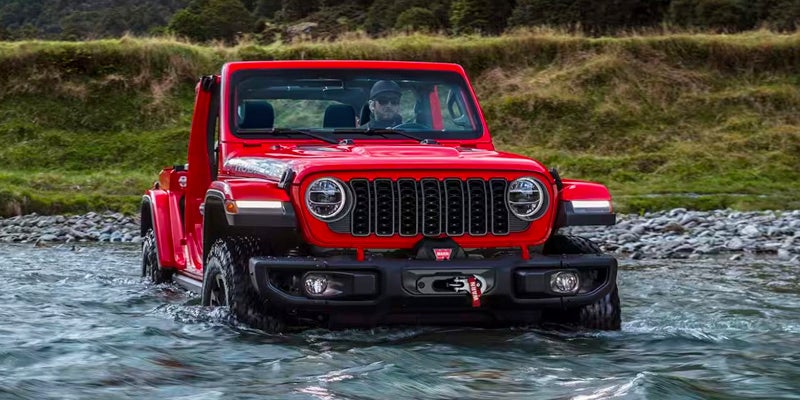 Red Jeep Wrangler driving through water